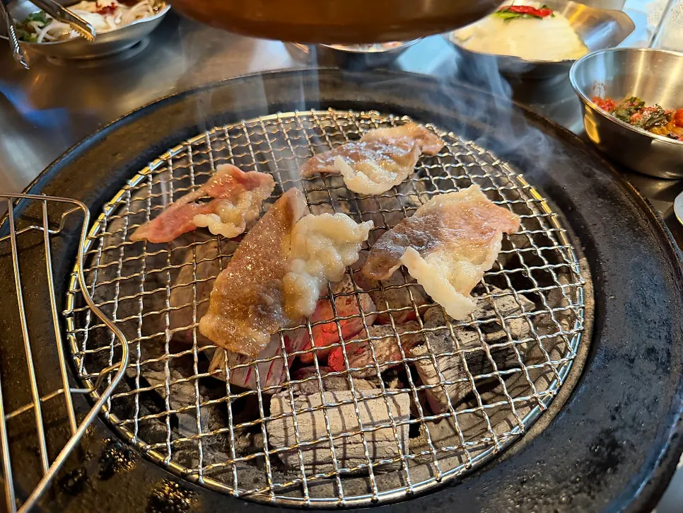 Charcoal-grilled brisket being flipped and grilled on both sides