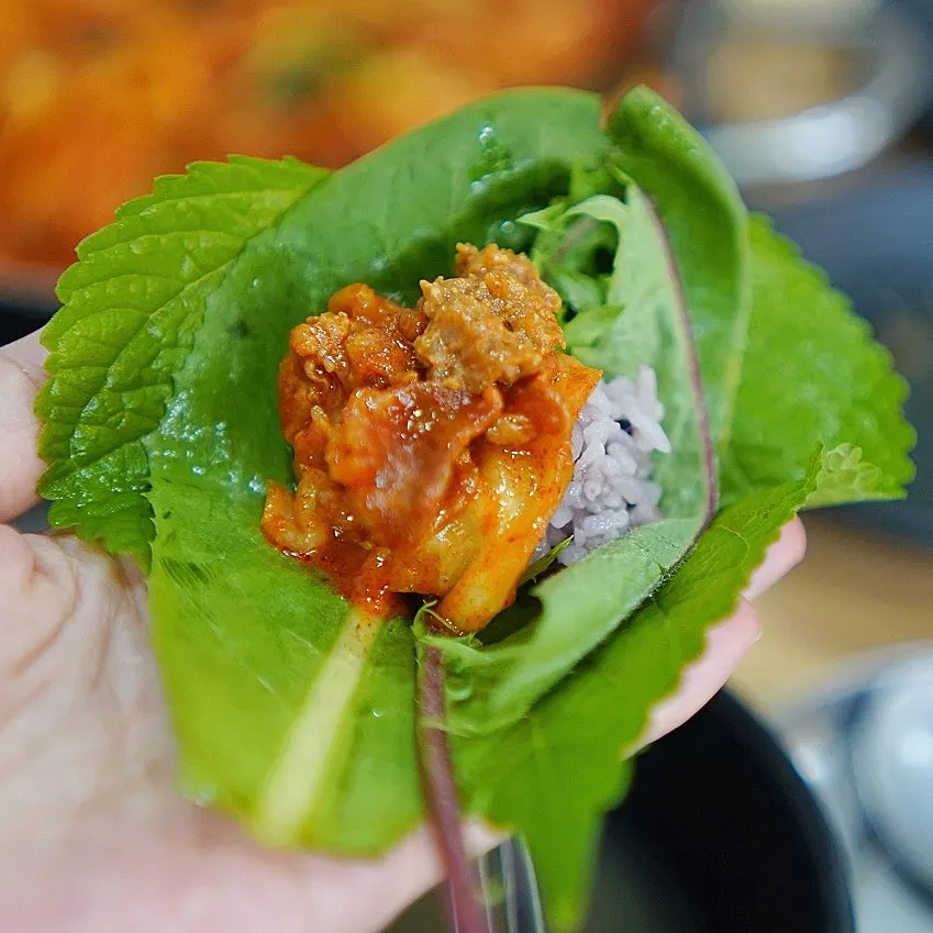 A piece of stir-fried pork placed on a ssam vegetable