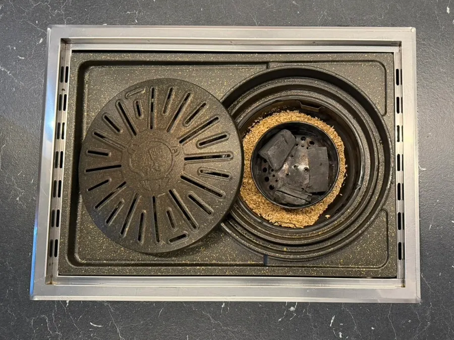 Grill pan smoking with charcoal and rice husks