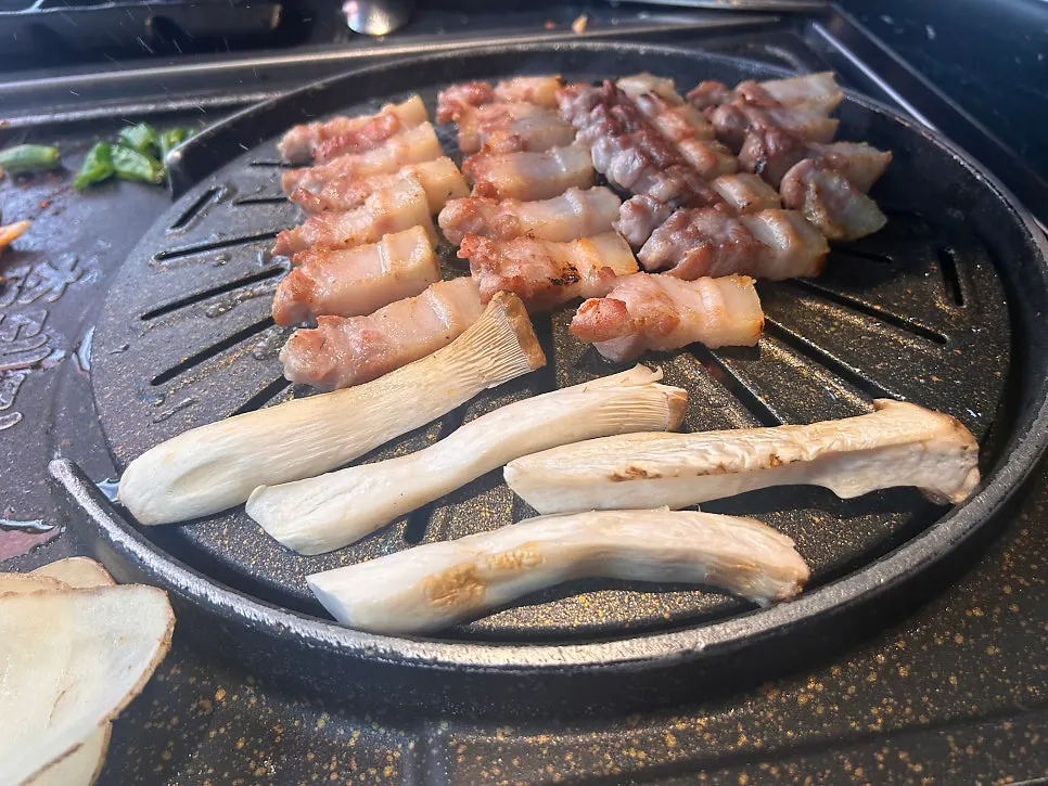 Grill with bean sprouts and kimchi cooking alongside the meat