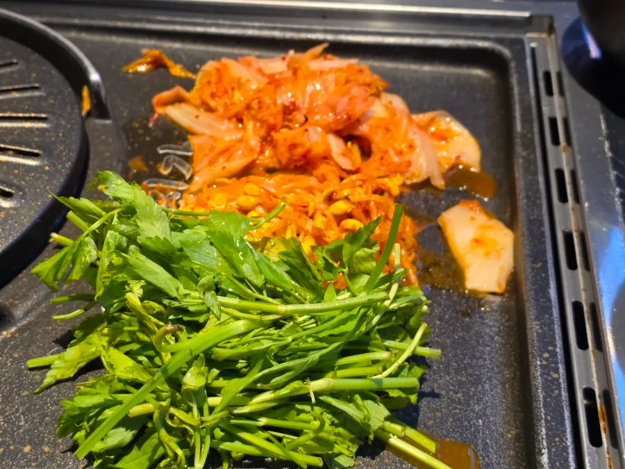 Side vegetables including minari, scallion salad, and bean sprouts