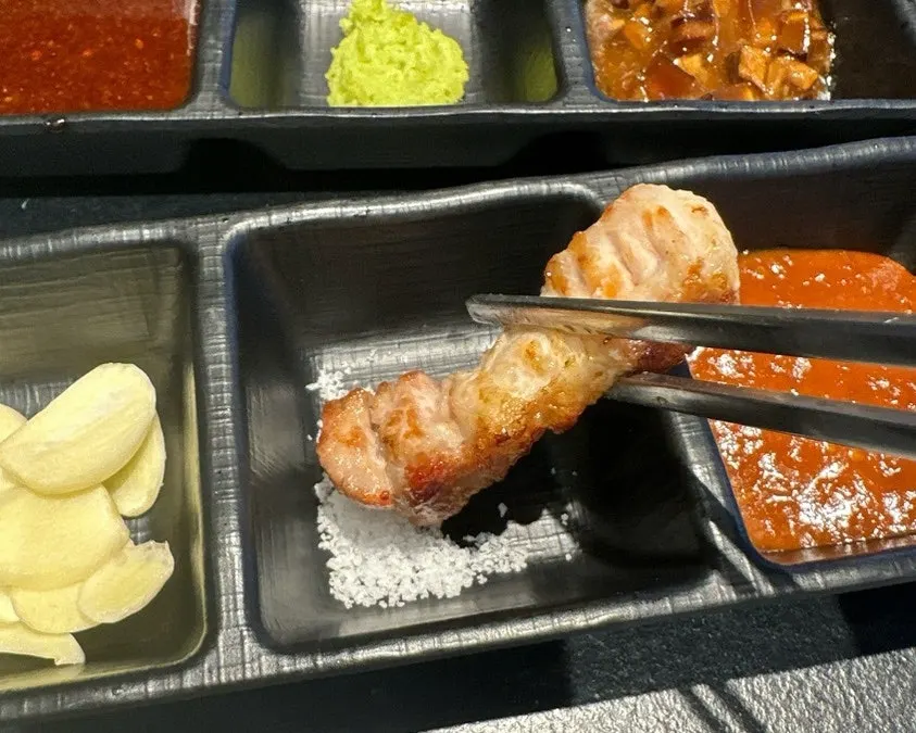 A crispy-outside, juicy-inside piece of pork belly dipped in salt