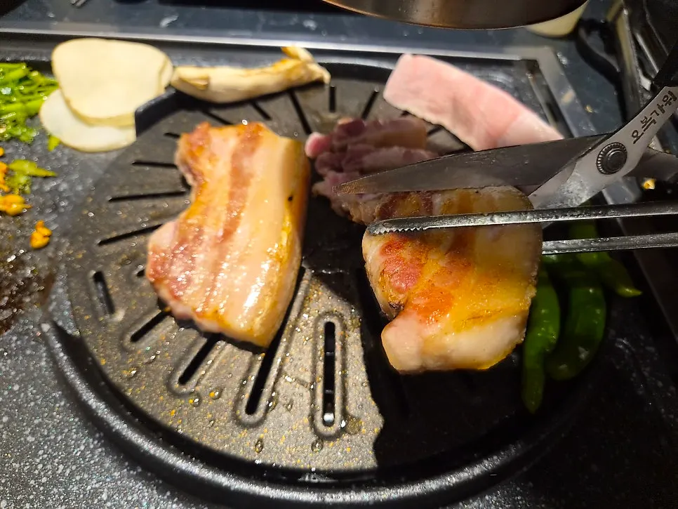 Staff grilling the ogyeopsal on the tabletop grill