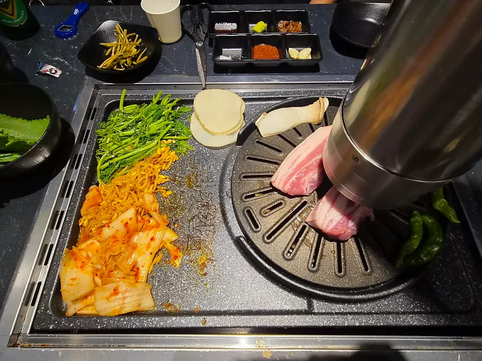 Minari, bean sprouts, kimchi and potato grilling together on the pan