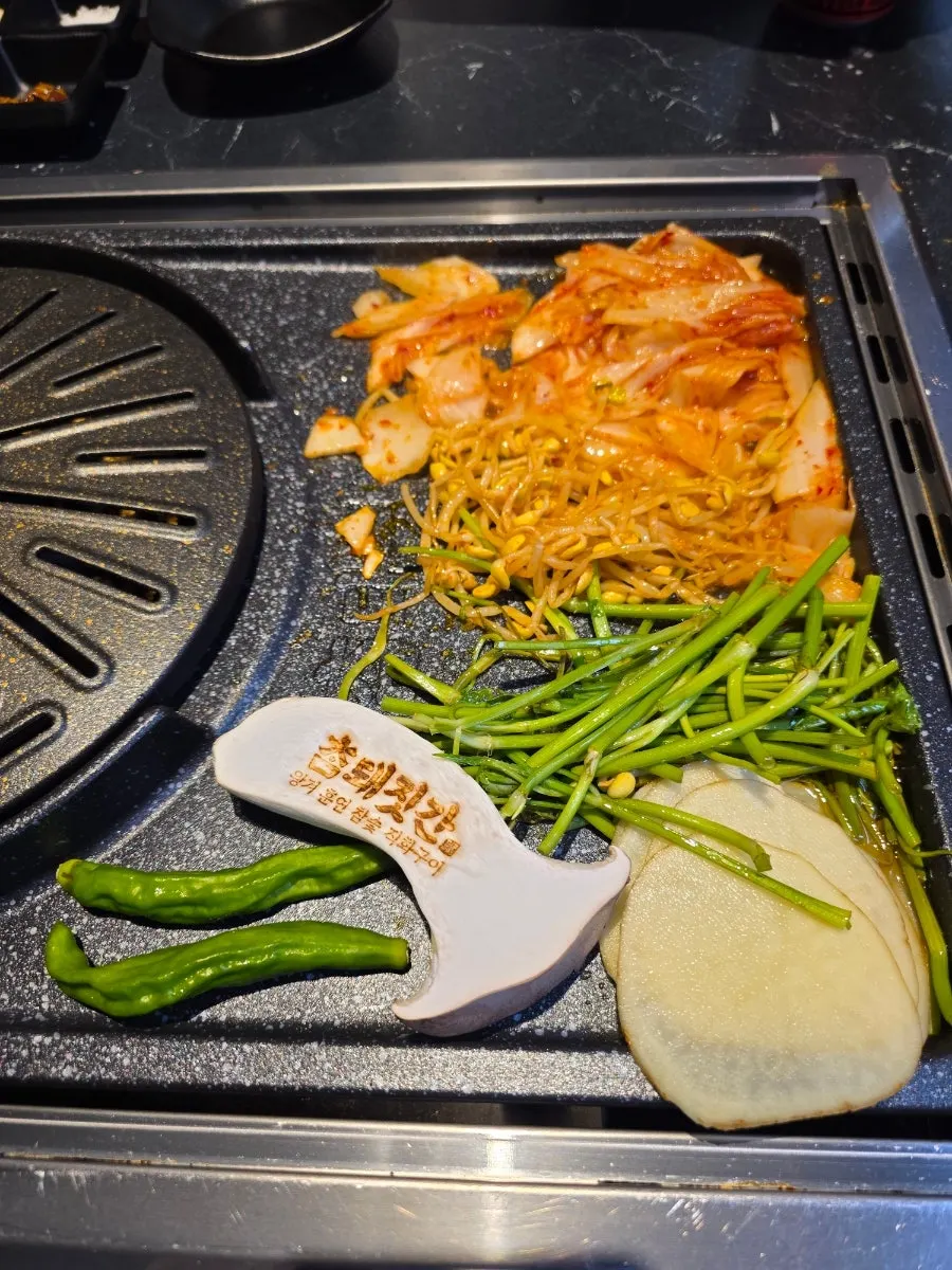 Kimchi, minari, and bean sprouts pre-set on the grill