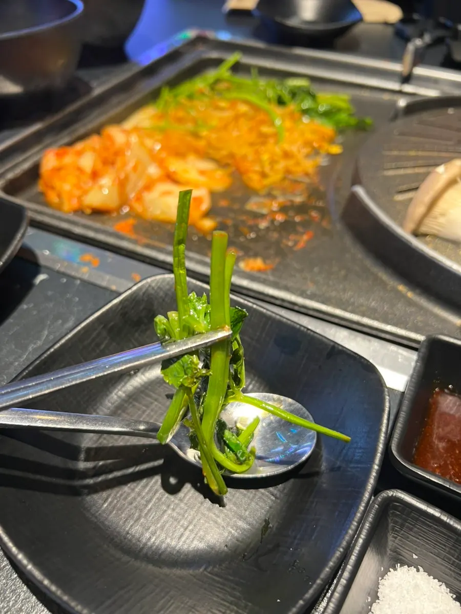불판 옆에 올려진 미나리와 김치, 콩나물