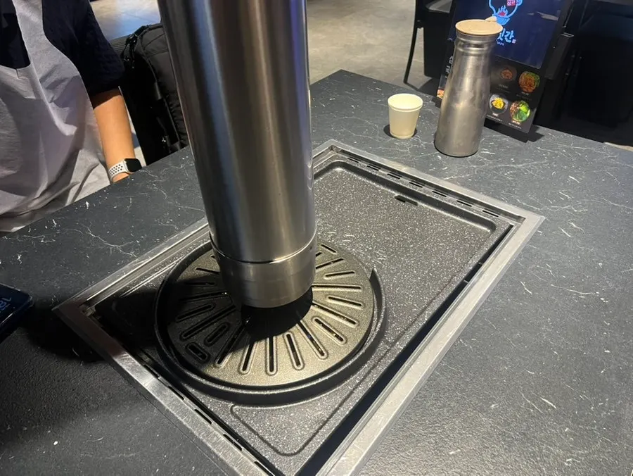 Table fitted with a large grill plate and smoke-extraction vent