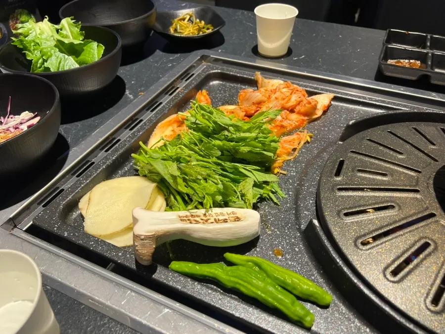 Kimchi, bean sprouts and potato placed on the grill first