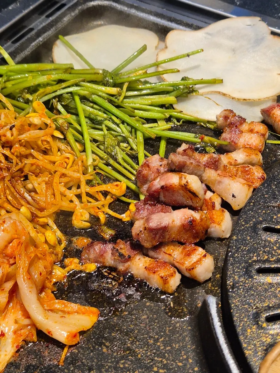 Pork belly grilling over a charcoal grill