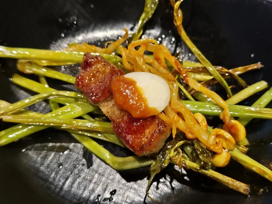 A wrap of pork belly topped with minari