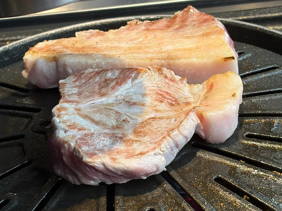 Pork belly and vegetables cooking on the grill