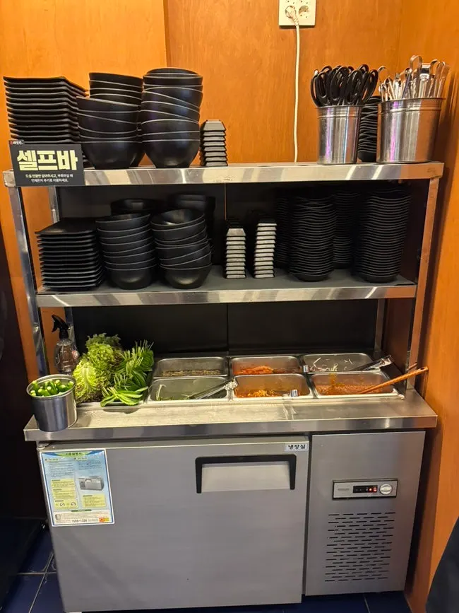 Self-serve side dish bar with minari, green onions, and garlic scapes