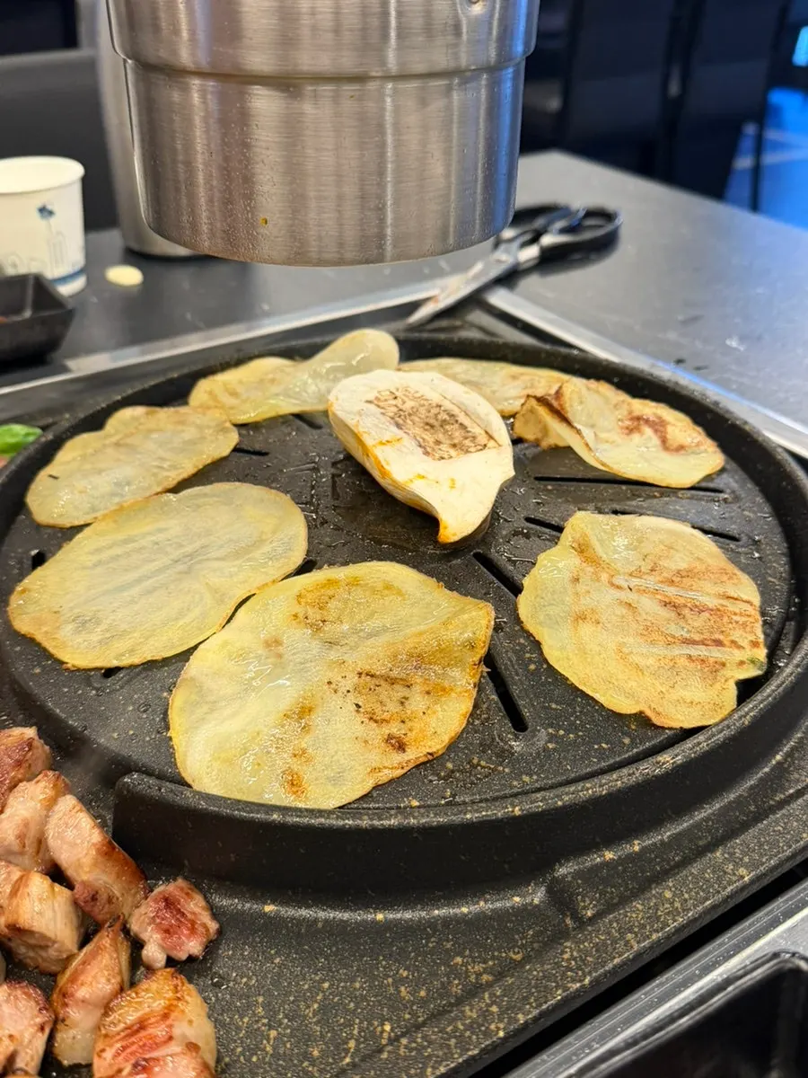 Thin potato slices grilling in meat fat