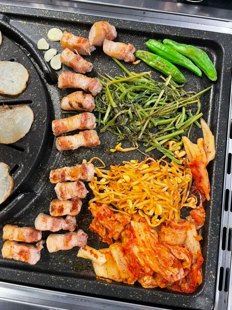 불판 아래에서 익는 김치와 콩나물, 미나리