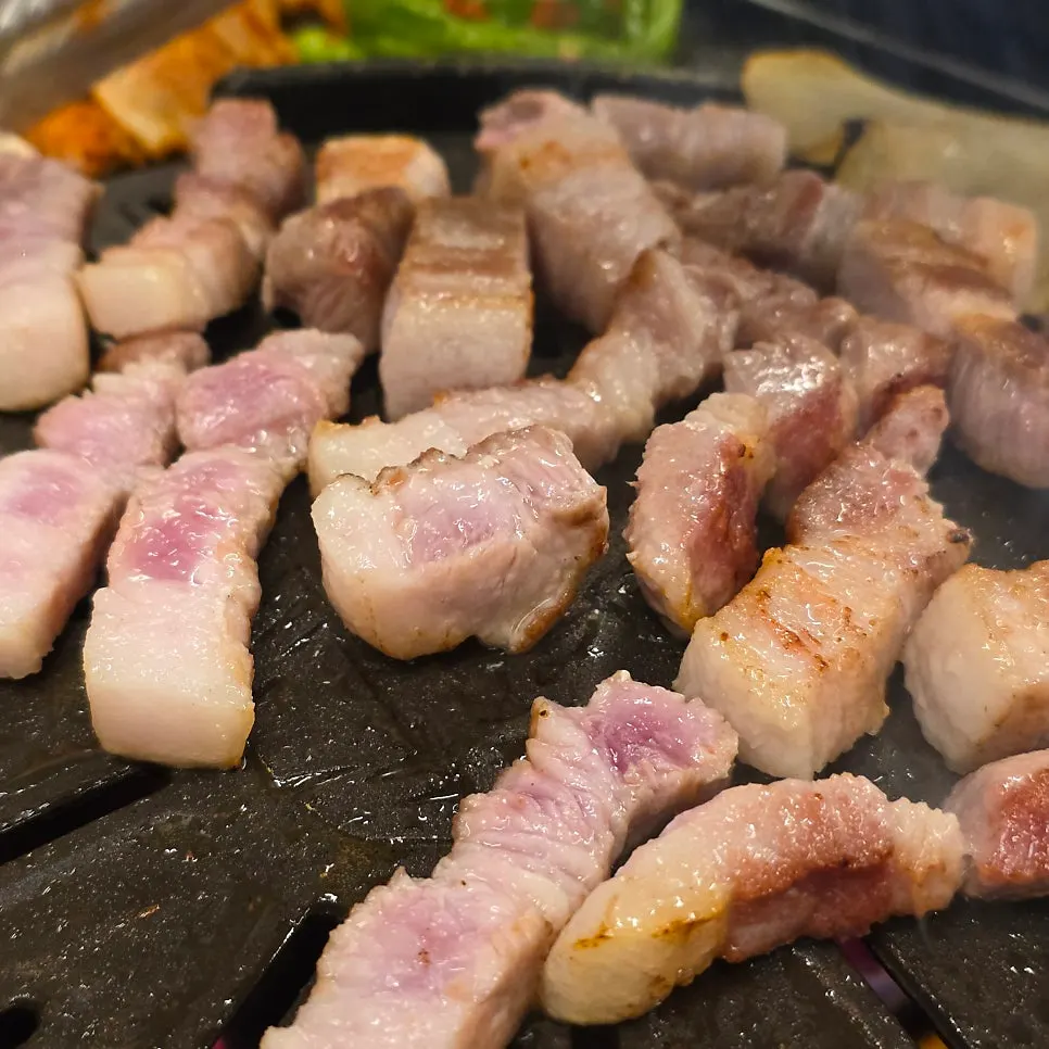 焼き上がったサムギョプサルとセリが乗った鉄板