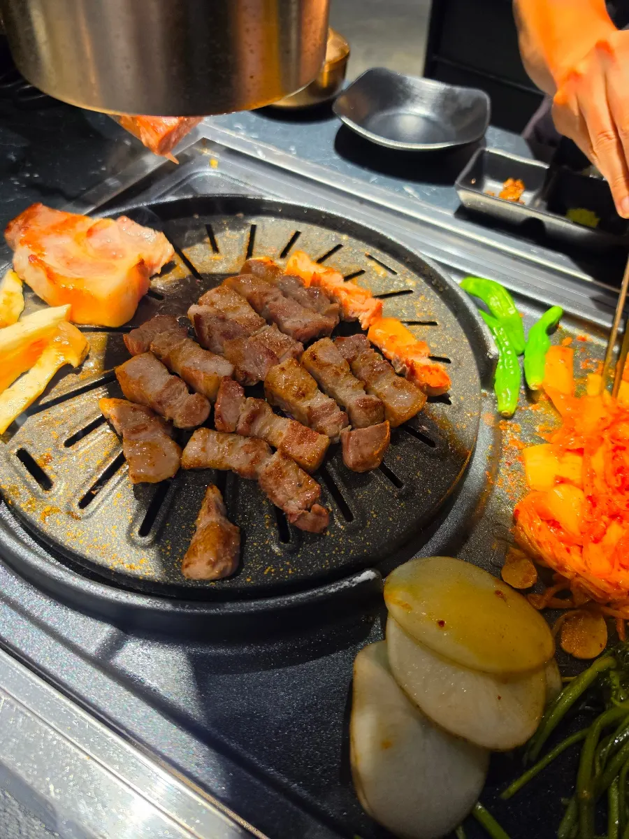 Samgyeopsal being flipped with tongs