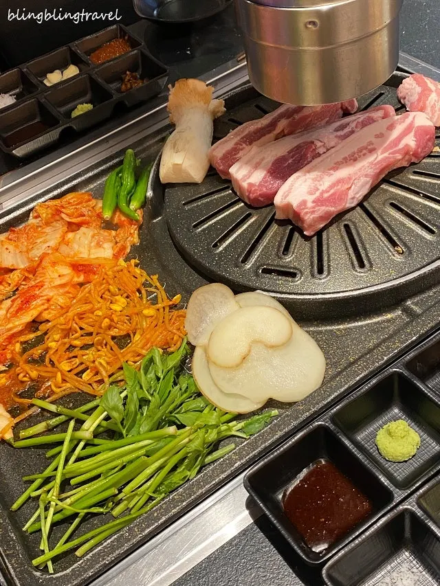 불판 한쪽의 김치와 콩나물, 미나리