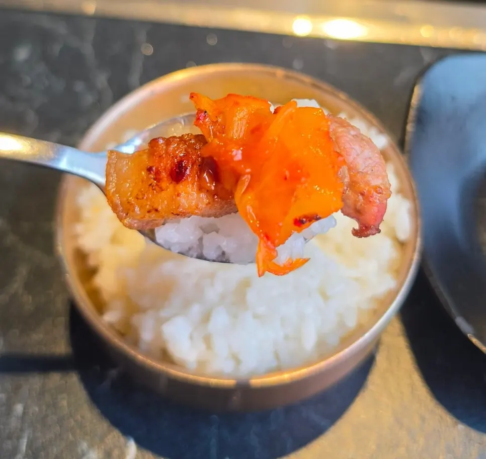 흰밥과 김치를 곁들인 오겹살 한 점