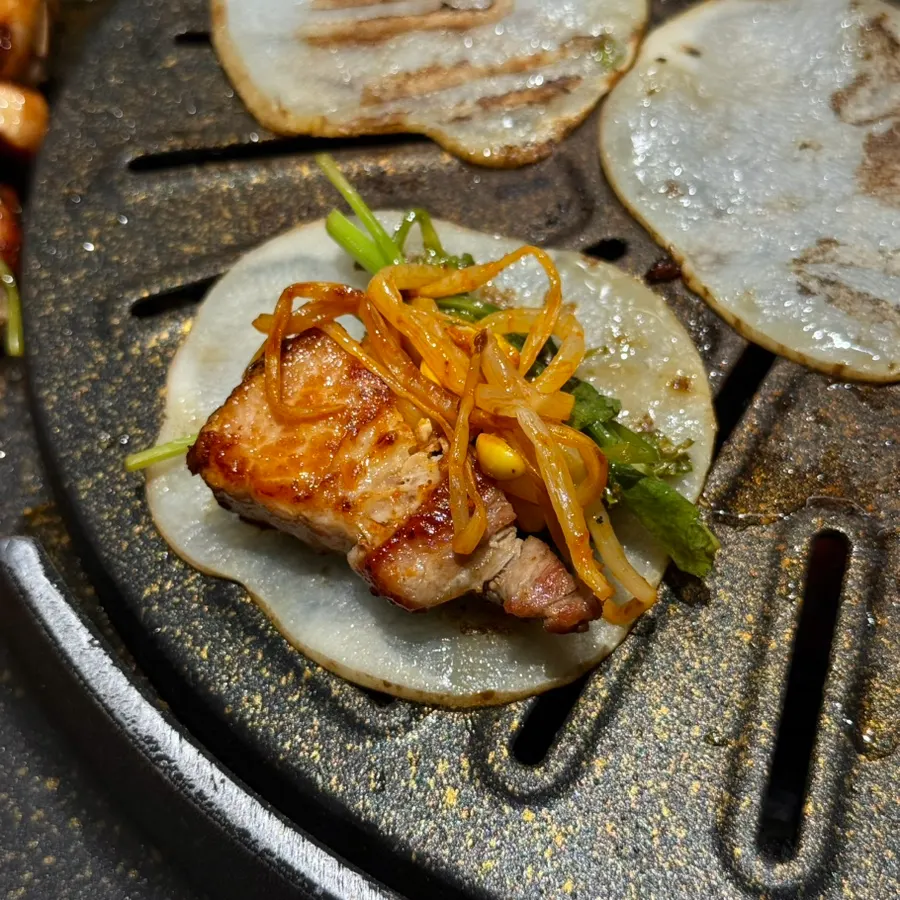 Pork belly wrap piled on a grilled potato slice