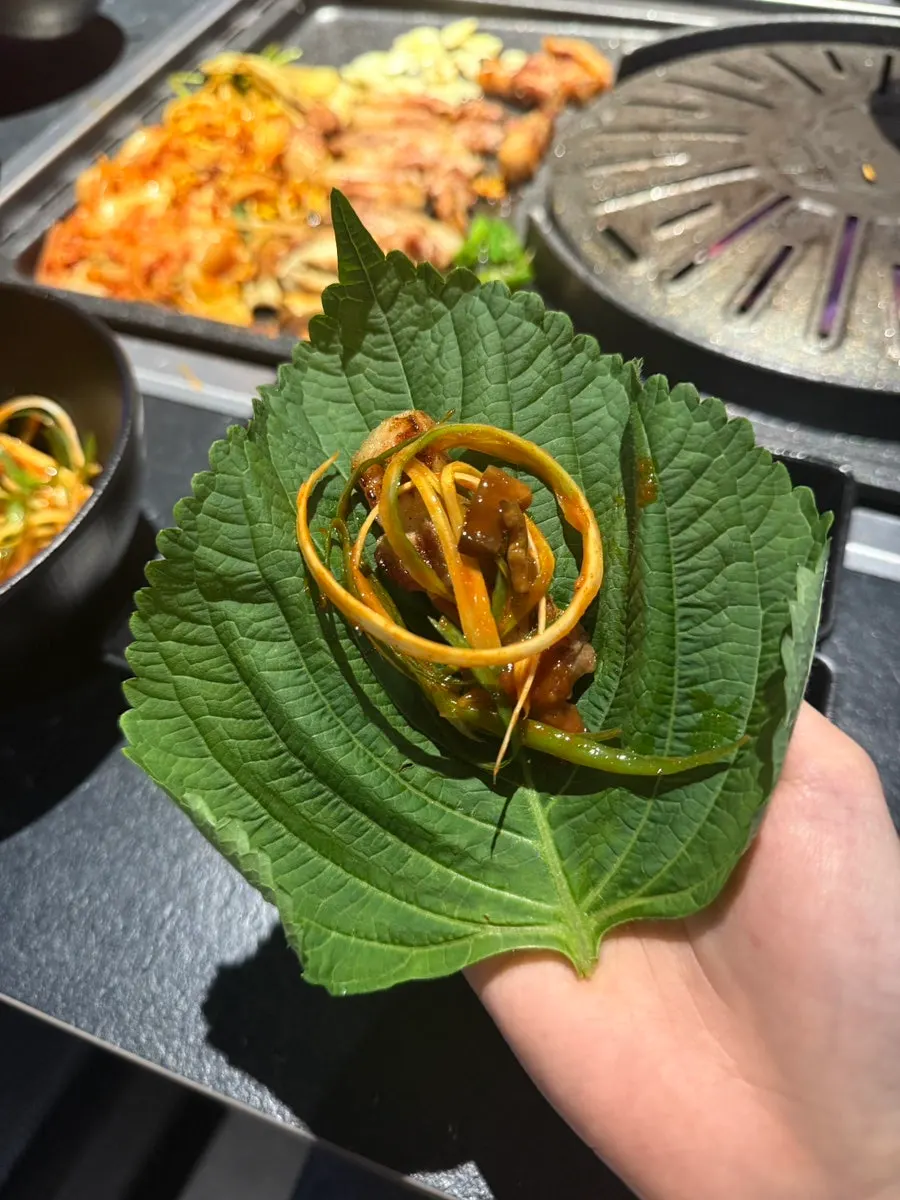 Potato wrap topped with pork belly, scallion strips and minari