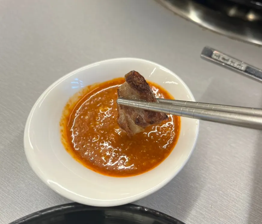 A piece of makchang dipped in sauce