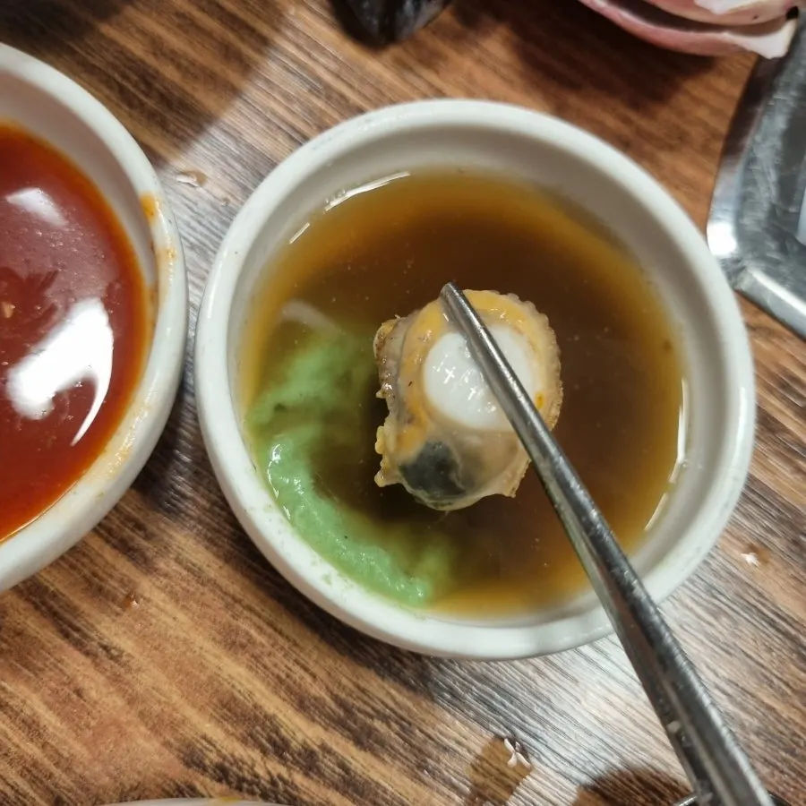 A piece of seafood dipped in vinegared gochujang