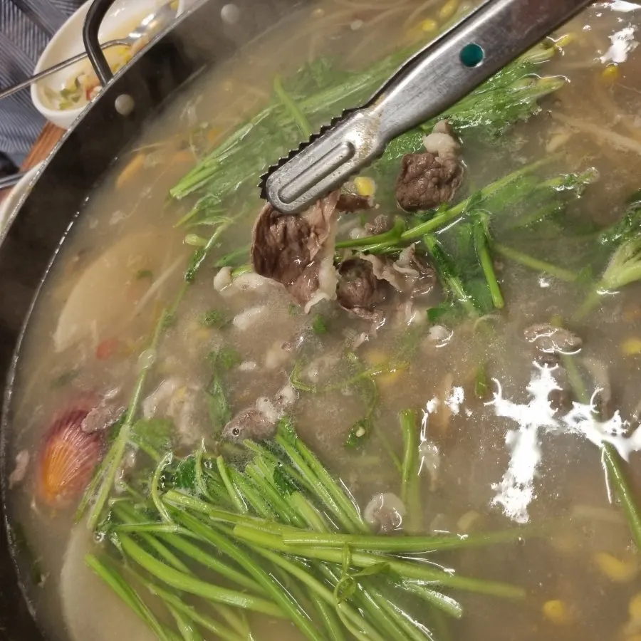 Beef brisket and minari being prepared for shabu-shabu