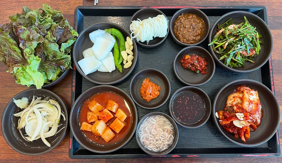 Table of side dishes for gukbap, including lettuce and kimchi