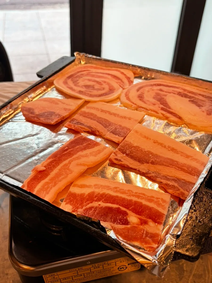 불판에 일렬로 올려진 냉동 삼겹살