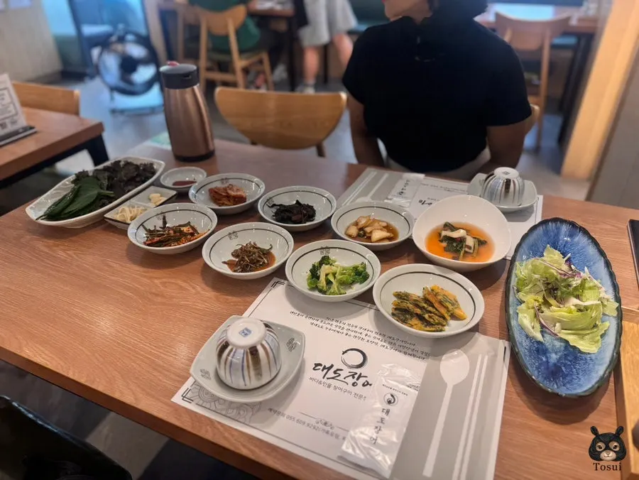 Side dishes at Daedo Jangeo, including salad and seasoned broccoli