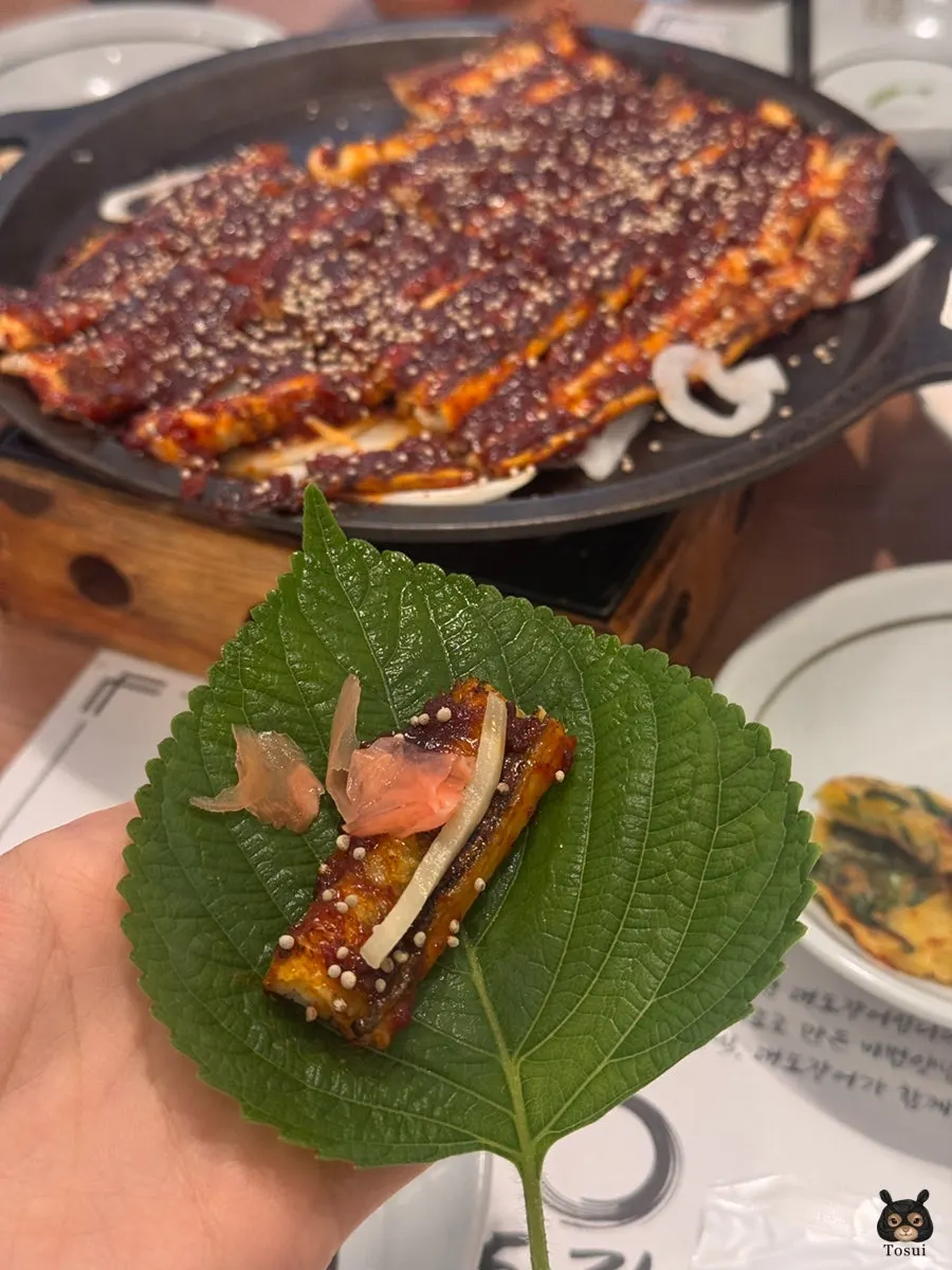 A piece of seasoned grilled sea eel picked up with chopsticks