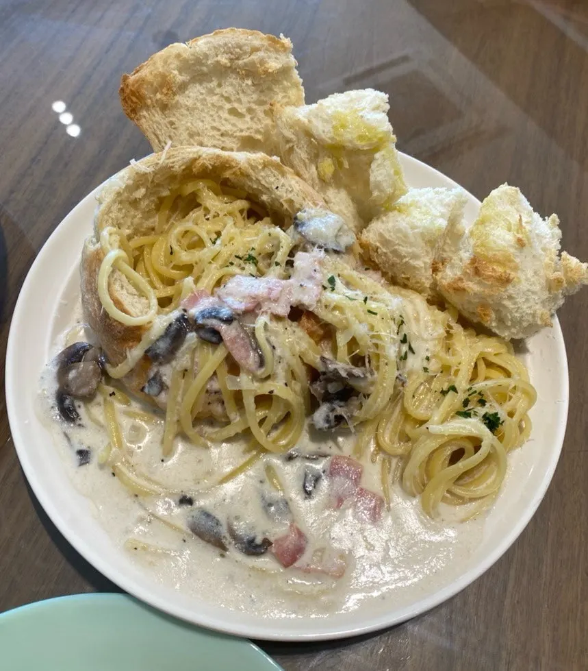 Table set with pasta, bread, and an americano