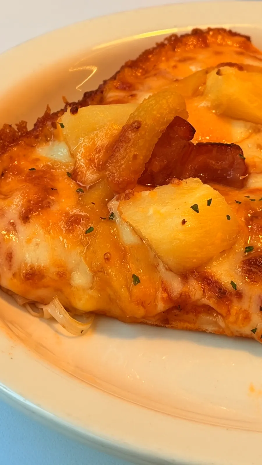 Pizza slice topped with bacon and pineapple