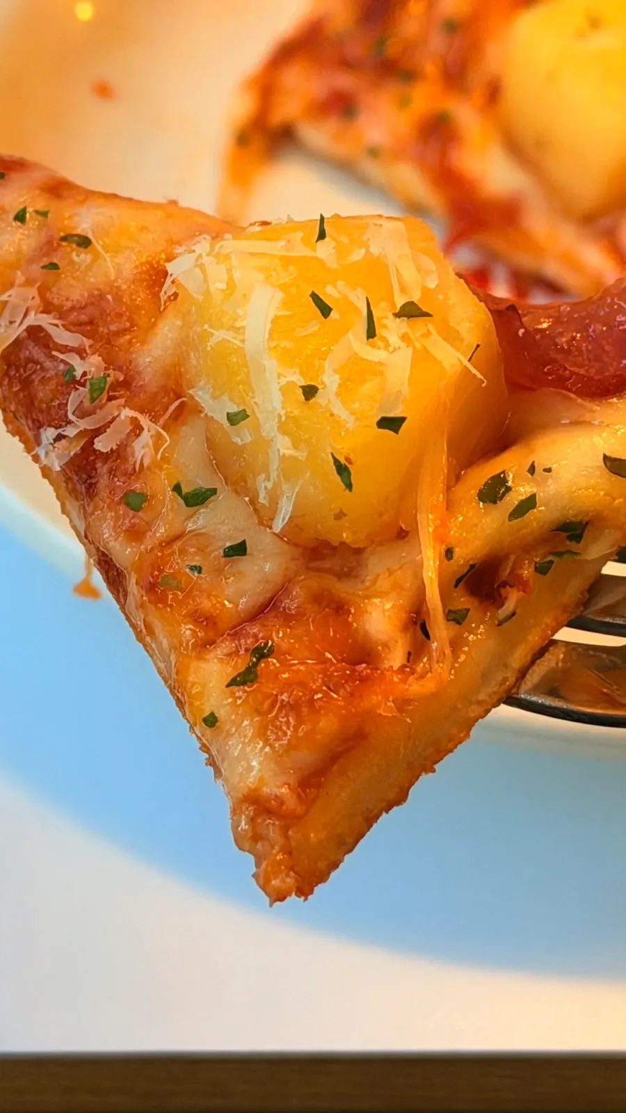A slice of Hawaiian pizza with stretchy cheese