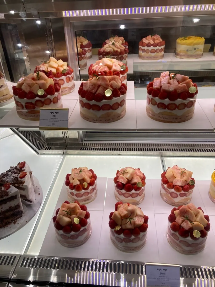 A pink-toned cake topped with strawberries and peaches