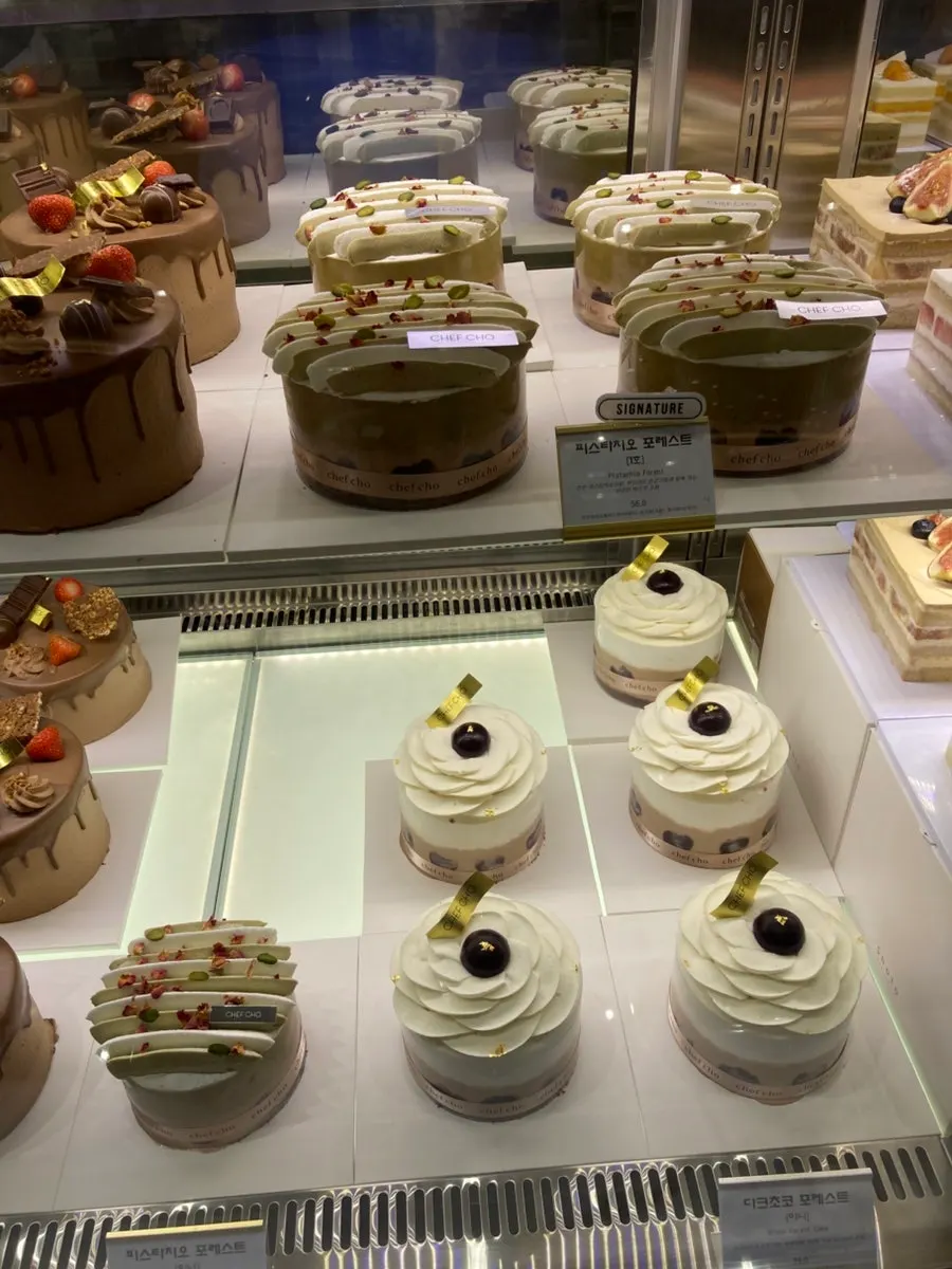 Several whole cakes lined up in Chef Cho's display case