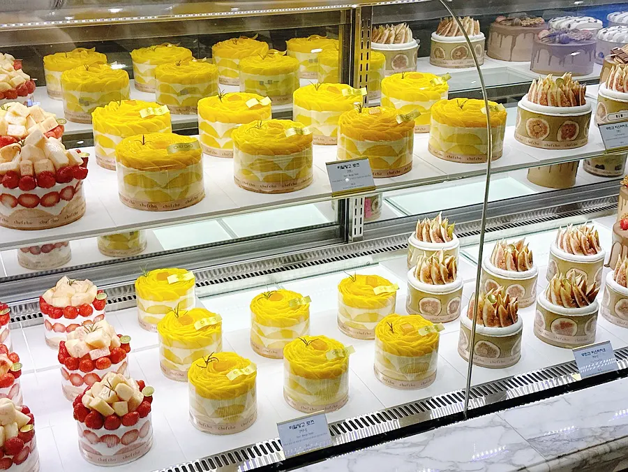 Mango and peach cakes lined up side by side in the display