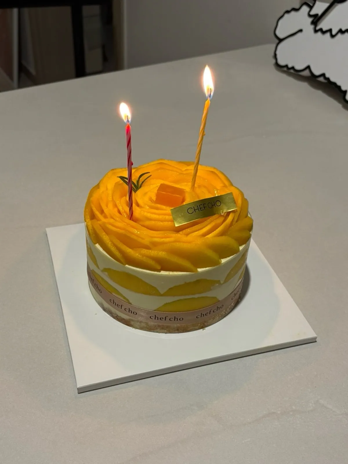 Real Mango Rose whole cake with lit candles