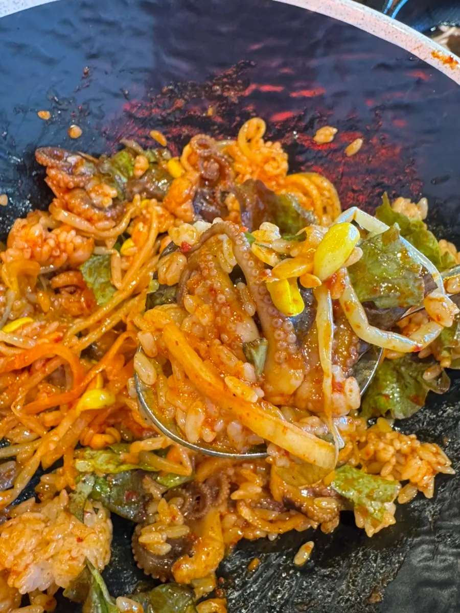 Bibimbap topped with lettuce, bean sprouts, radish salad, and jjukkumi