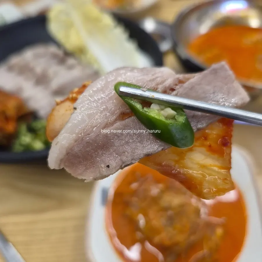 A wrap of bossam pork on a leaf of alba napa cabbage