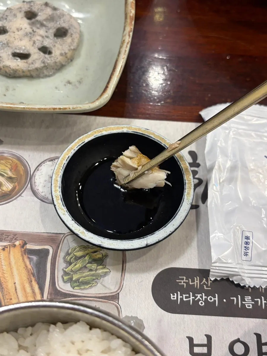 A piece of grilled fish dipped in soy sauce