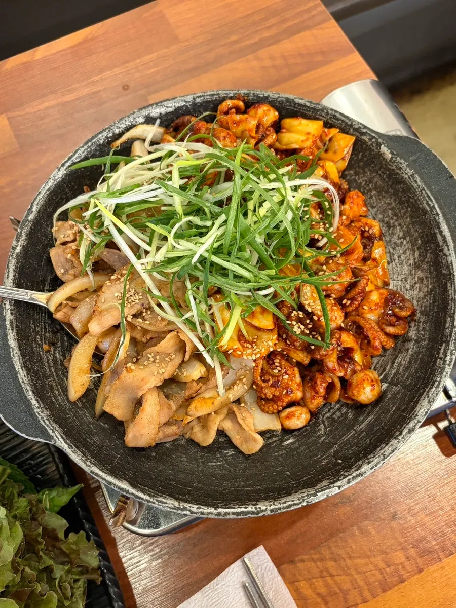 Pot of jjukkumi samgyeopsal topped with plenty of scallions