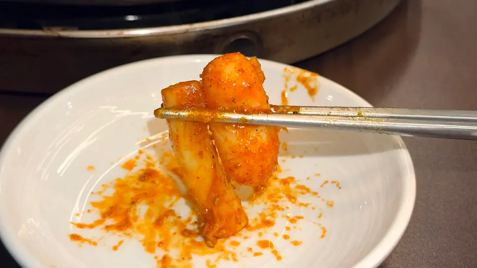 A piece of dakgalbi wrapped in melted cheese