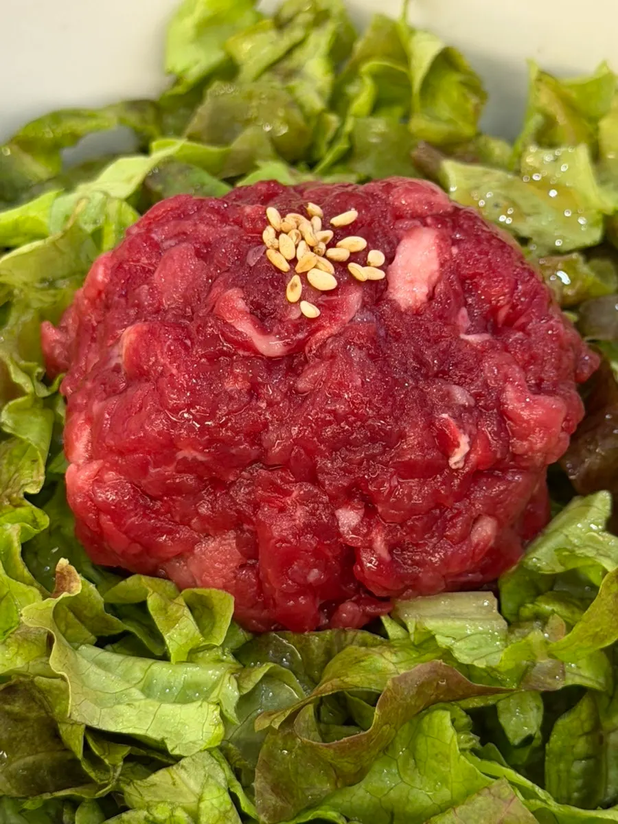 Yukhoe bibimbap topped with lettuce and raw seasoned beef