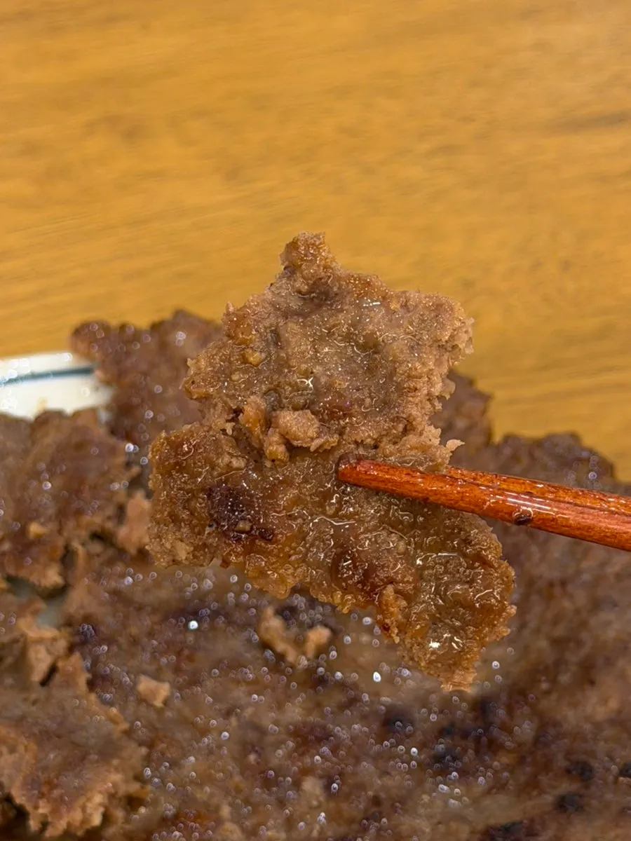 A piece of hanpan galbi cut and held with chopsticks