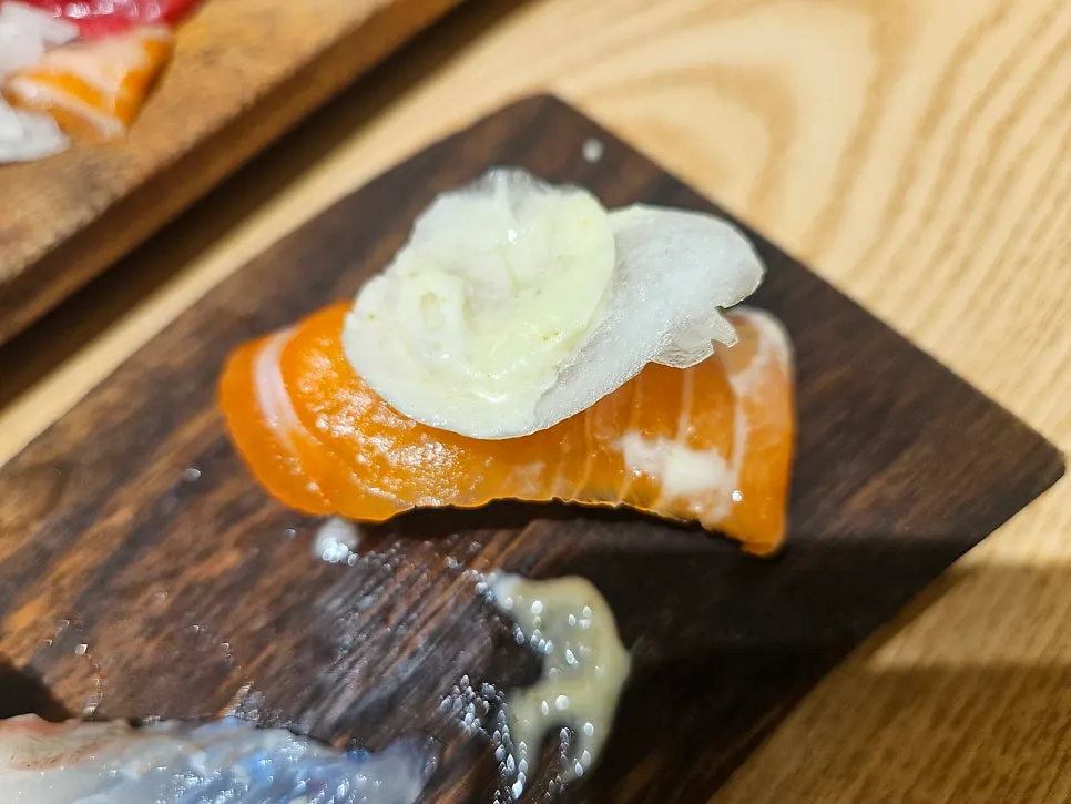 Salmon sushi topped with onion and sauce
