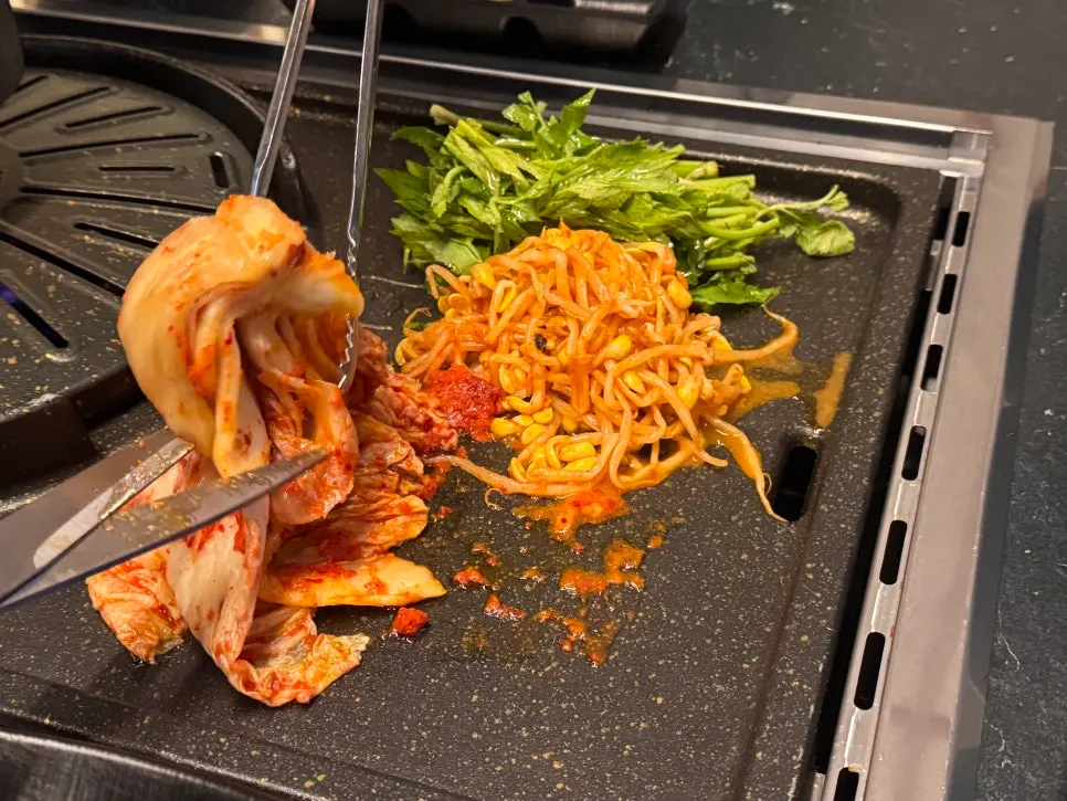 Grilling kimchi, bean sprouts, and minari set on the table