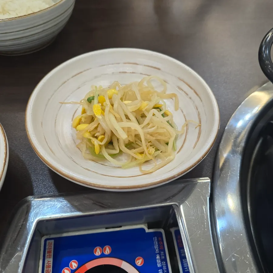 A ladle of budae-jjigae broth and sausage