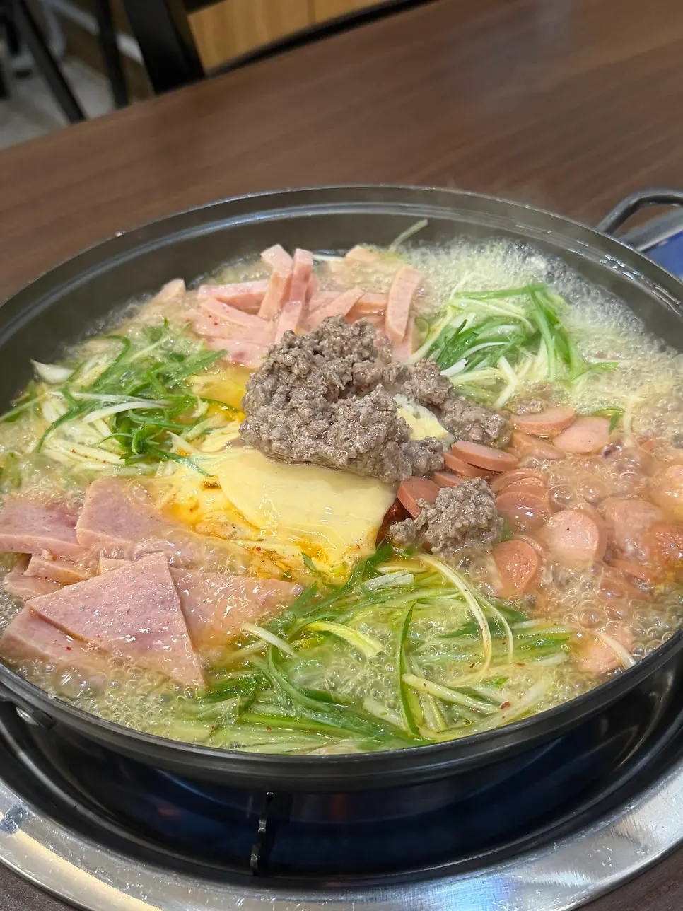 Pot of budae-jjigae with ham, sausage, and cheese before boiling