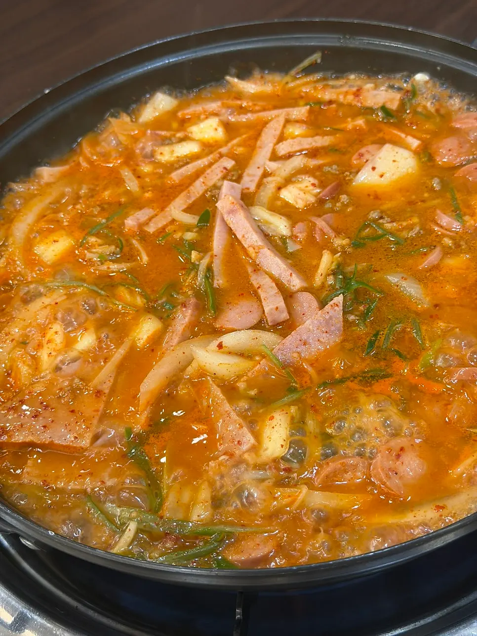 A ladleful of ham and sausage scooped from the pot